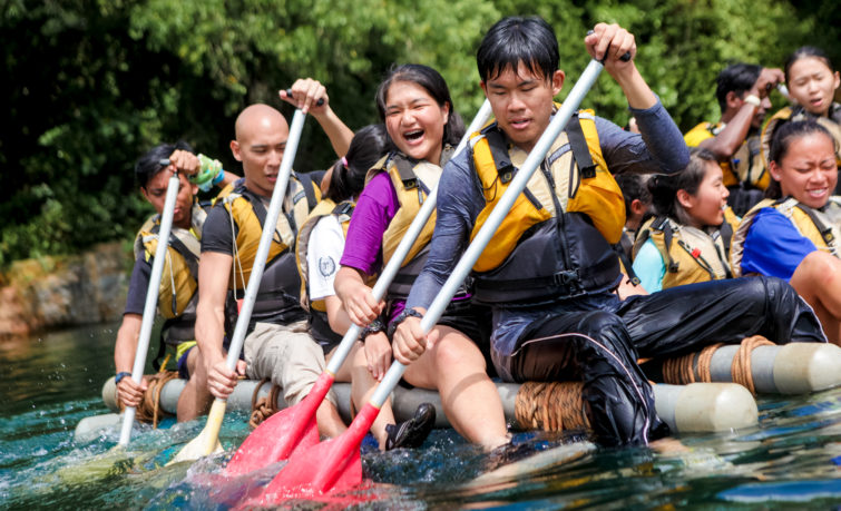 Youth paddling bamboo raft